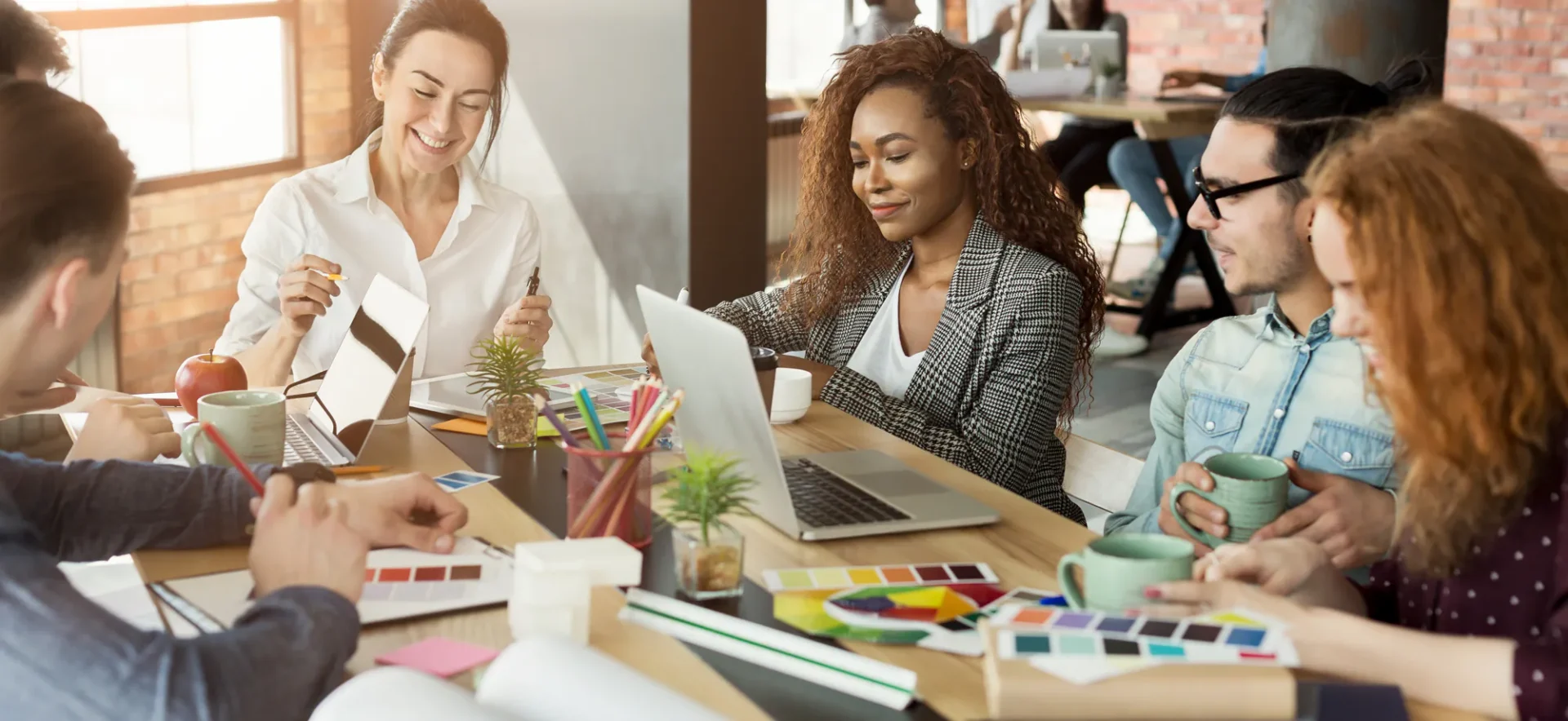 A creative team collaborating around laptops in a modern workspace